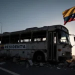 Figure walking away from bus with suitcase and flag in background showing Venezuela