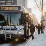 SEPTA bus unloading passengers with snow-covered streets and early morning light in Philadelphia.
