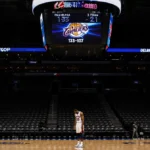 Lone Sixers player stands defeated in empty arena with scoreboard showing 133-107 loss