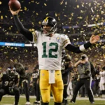 Aaron Rodgers holding the ball aloft with confetti raining and ecstatic Steelers fans cheering in the stadium.