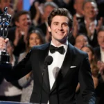 Timothée Chalamet holds Critics Choice Awards trophy with velvet pedestal and warm glow while Kylie Jenner watches from wings