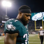 Trent Williams stands alone on the field with downcast eyes and a referee