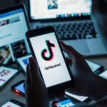 Person holding smartphone with UpSquared app open and looking at TikTok logo with red X on screen against technology icons